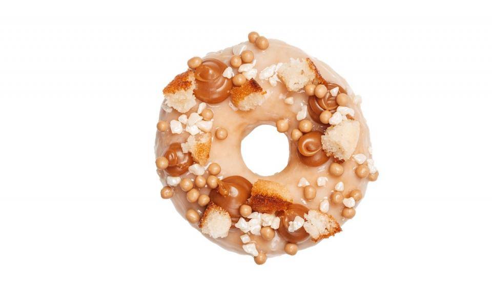 A donut with caramel glaze, dabs of caramel fillings, cake pieces and Crispearls™