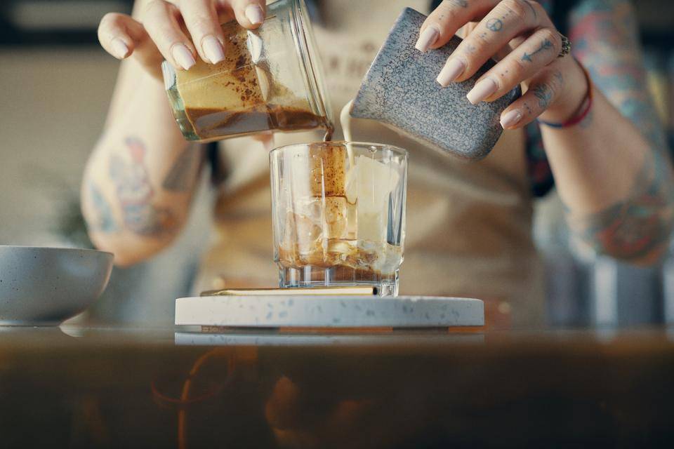 A server pours cream and a chocolate together to create a decadent beverage