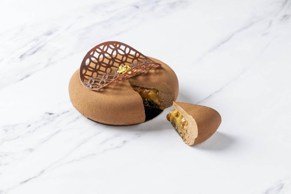 A chocolate entremet coated with milk chocolate spray and topped with a chocolate garnish