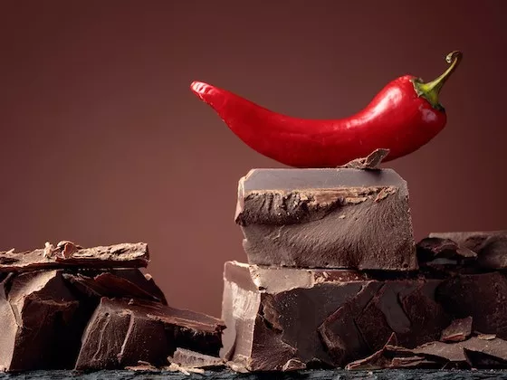 Red chili pepper on a stack of chunks of dark chocolate