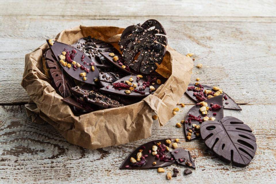 Round and leaf-shaped chocolates with nuts and seeds in a natural brown paper-like bowl