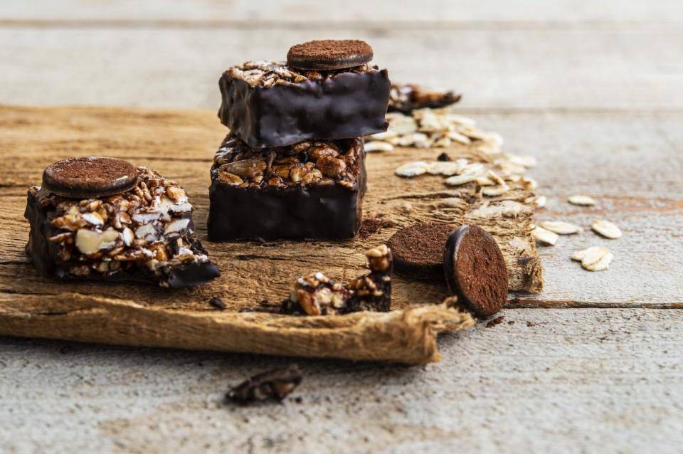 a collection of dark couverture-dipped energy bars with seeds and nuts on a wooden board