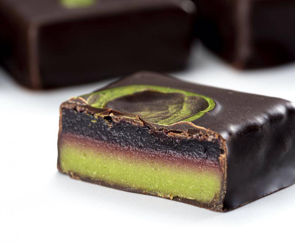 An enrobed bonbon sliced in half, showing red and green layers