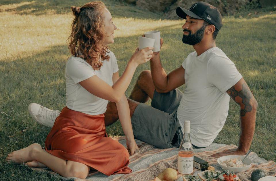 A man and a woman toast while enjoying a picnic