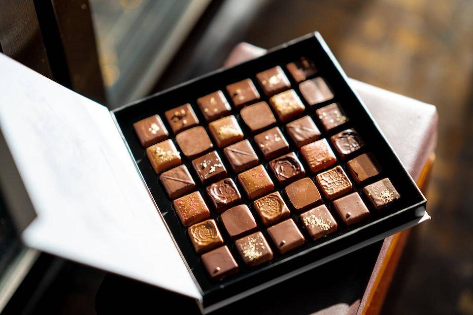 Large box of assorted chocolates open on a bench