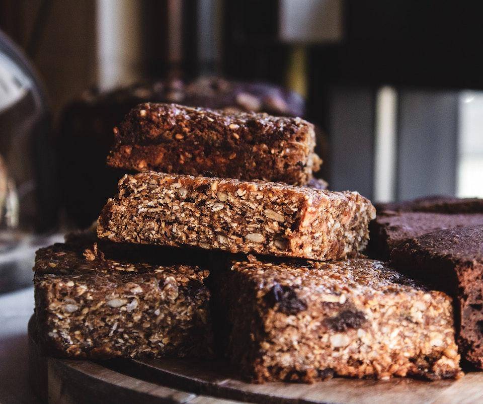 A stack of granola-bar style brownies with visible oats and seeds