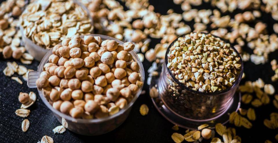 an overflowing glass bowl of chickpeas next to an overflowing glass jar of hemp seeds