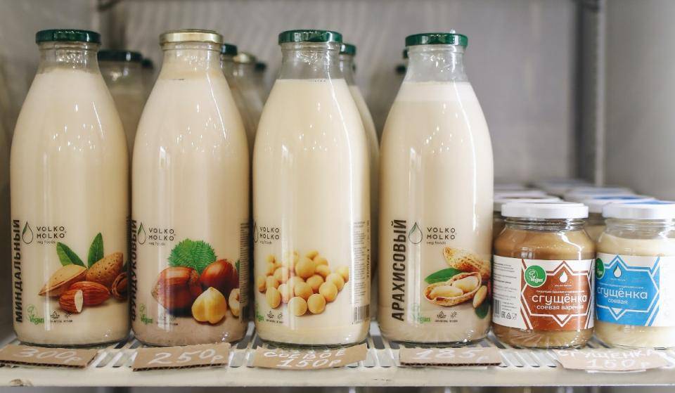 A shelf with four bottles of different plant-based milks