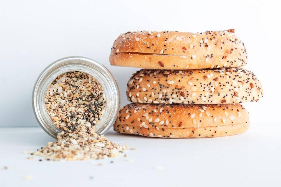 A stack of Everything bagels next to a tipped-over jar of Everything Bagel seasoning