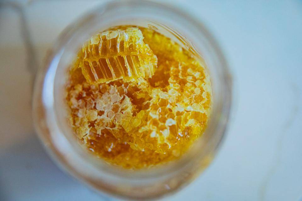 Looking down into an open glass jar filled with honey comb
