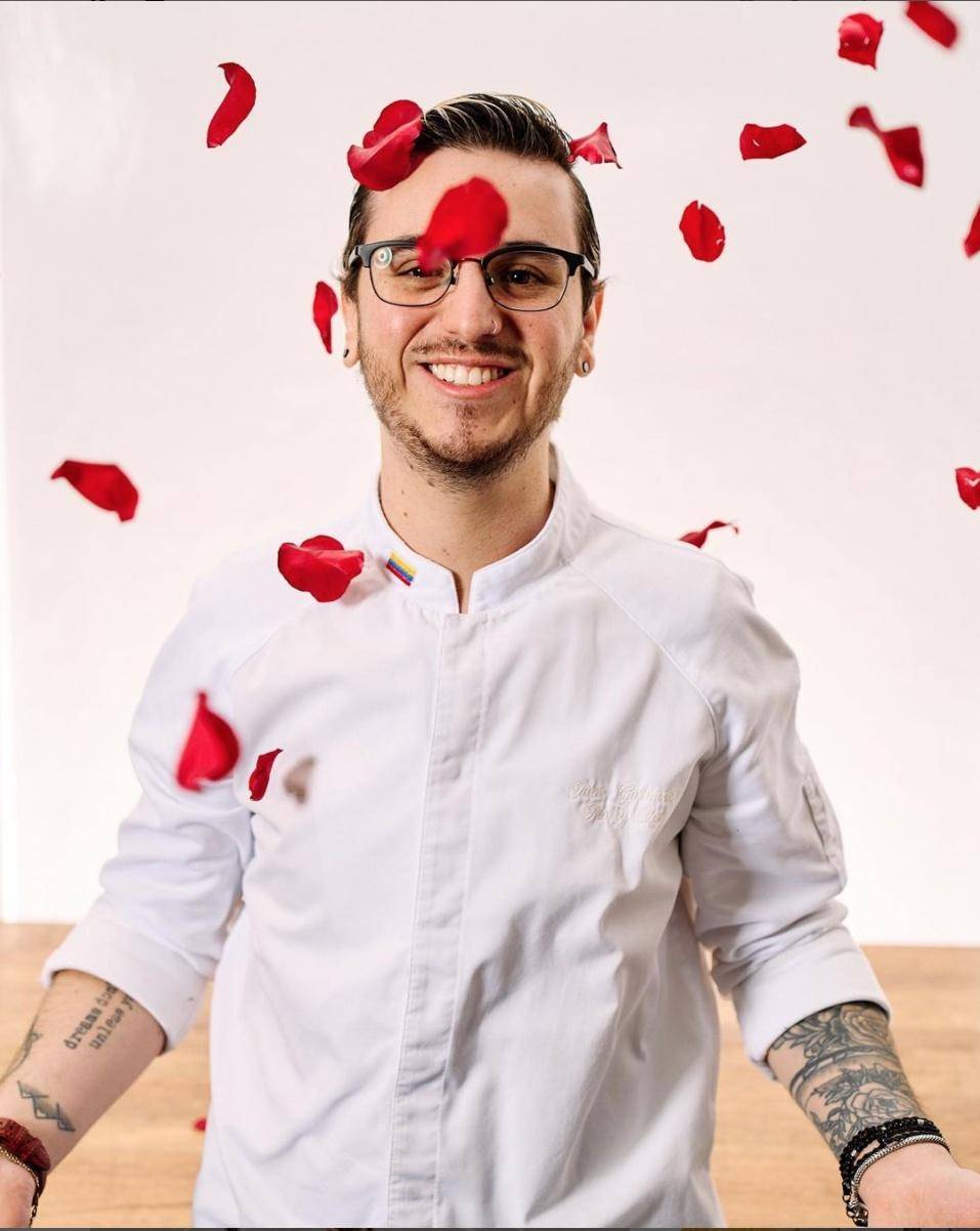 Chef Juan Gutierrez, smiling, in a shower of rose petals