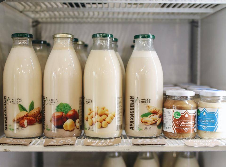 Glass bottles containing plant-derived milks in a refrigerated case