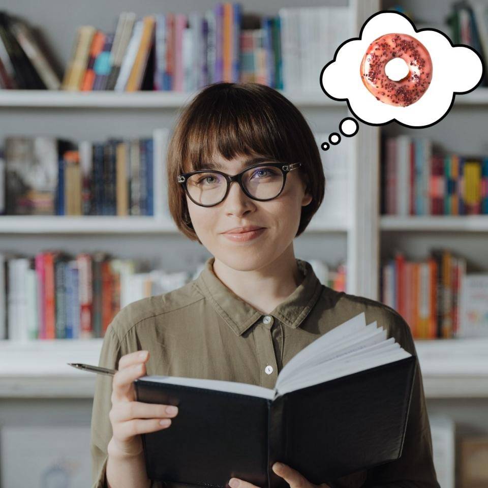 A lady with thick glasses, holding a book and thinking about how to spell "donut"