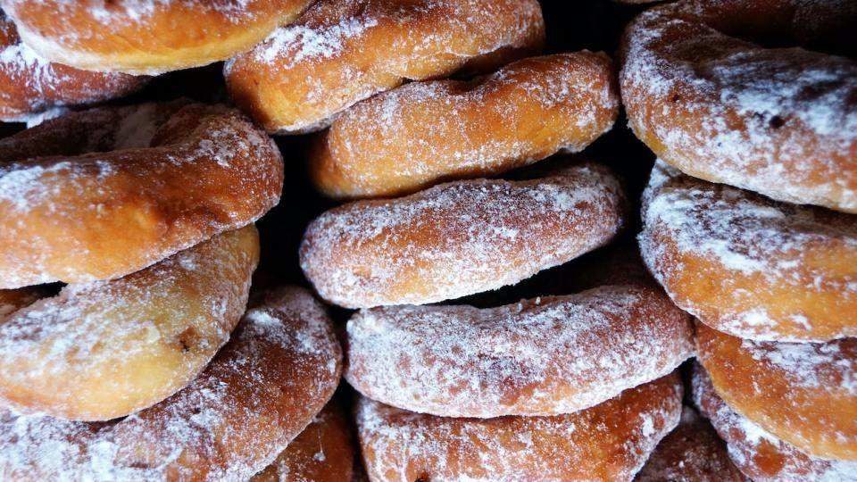 Stacks of plain, somewhat rustic donuts dusted with powdered sugar
