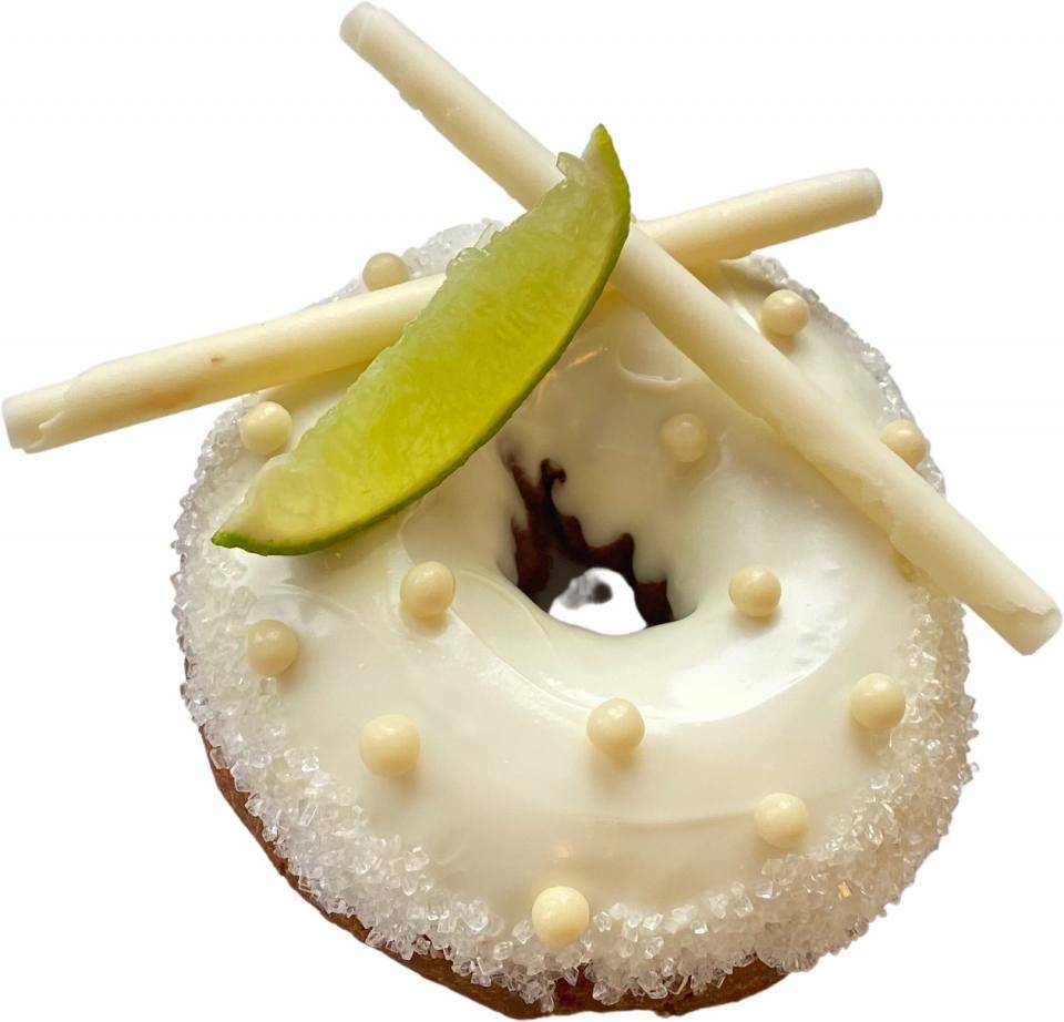 A donut with white glaze, a lime slice and chocolate garnishes