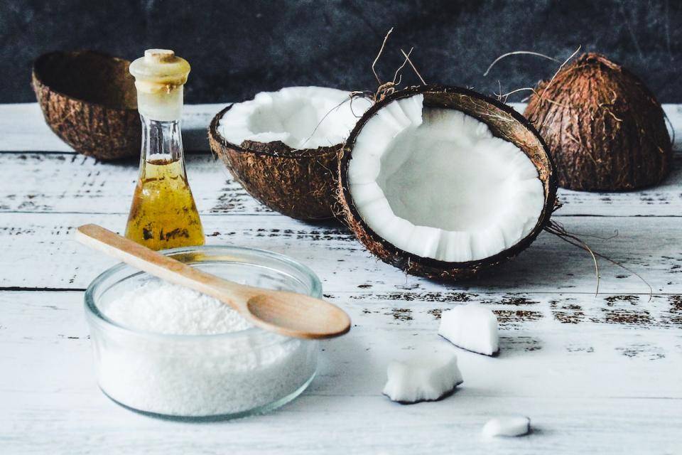 Split coconuts, solid and liquid coconut oil on a tabletop