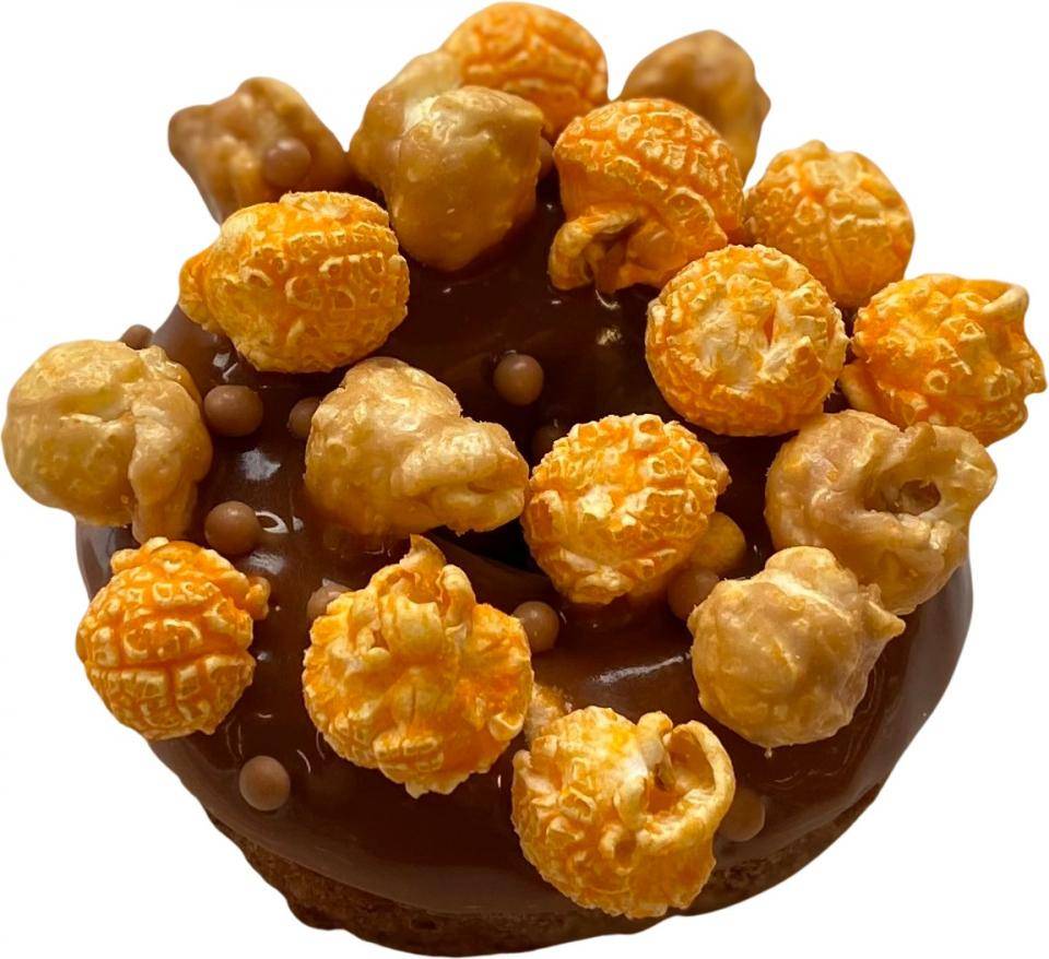 A chocolate doughnut garnished with caramel and cheese popcorn 
