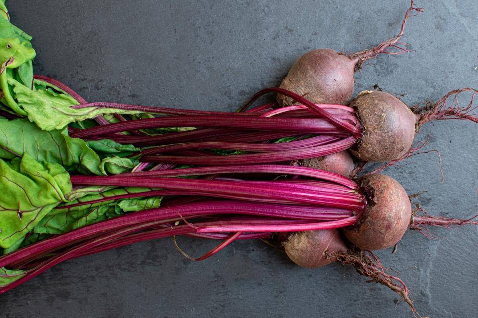a bunch of beets with stems and greens on a tabletop