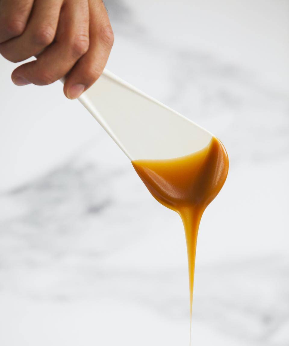 Caramel filling of a precise thickness falls from a spatula