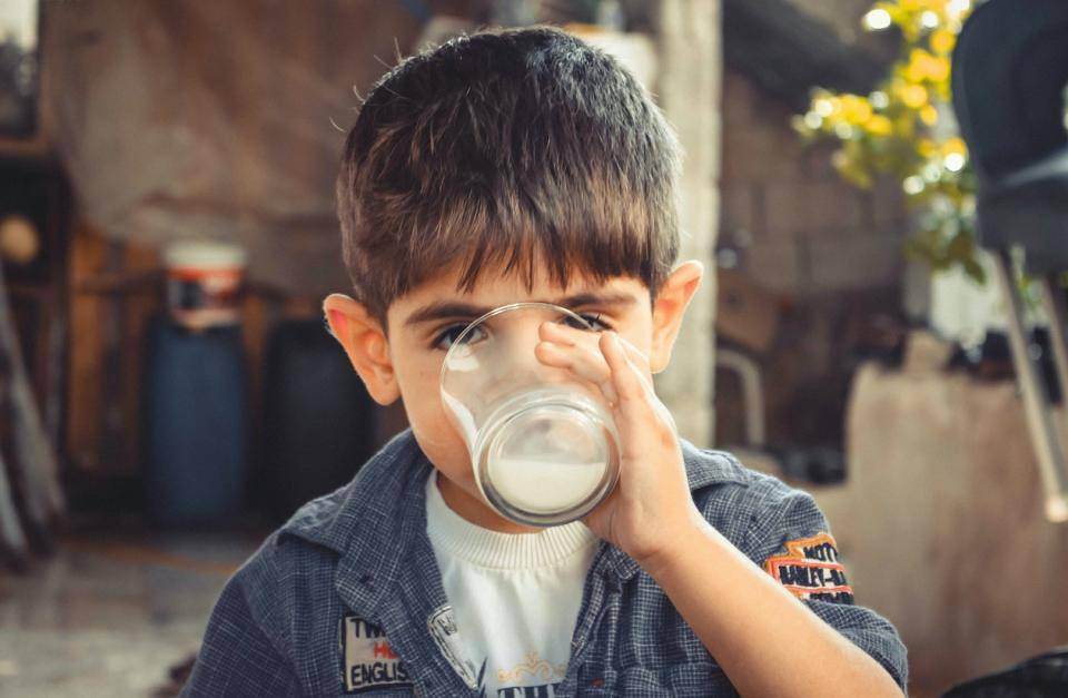 A small child drinking a glass of milk