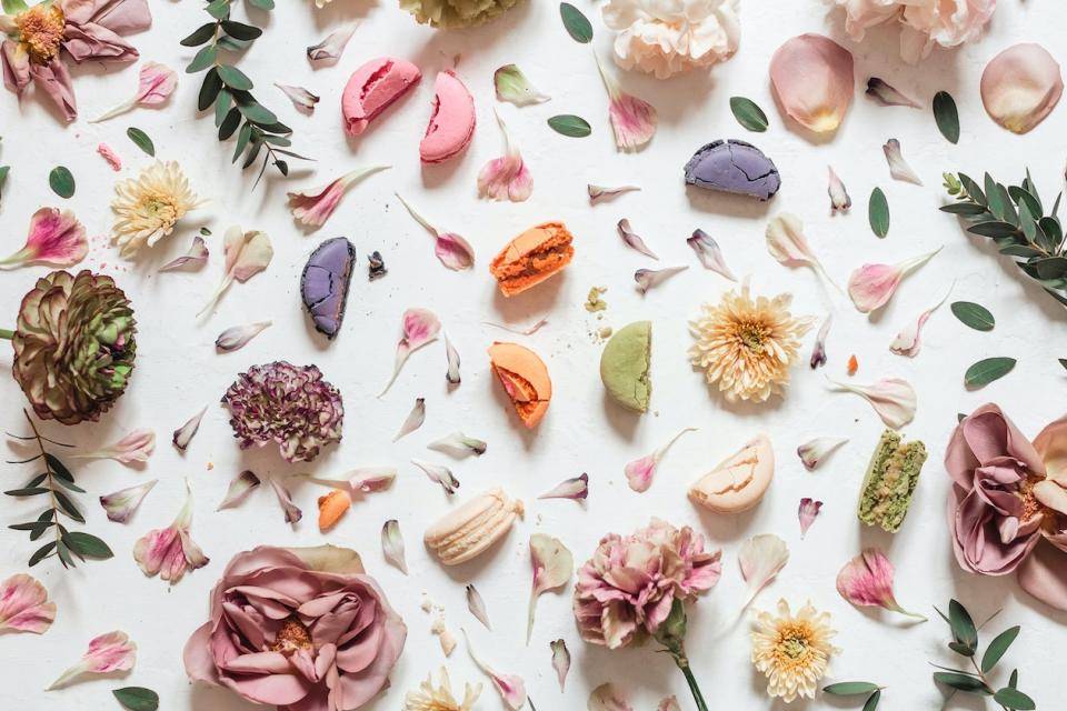 Flower petals and herbs scattered among halved macarons