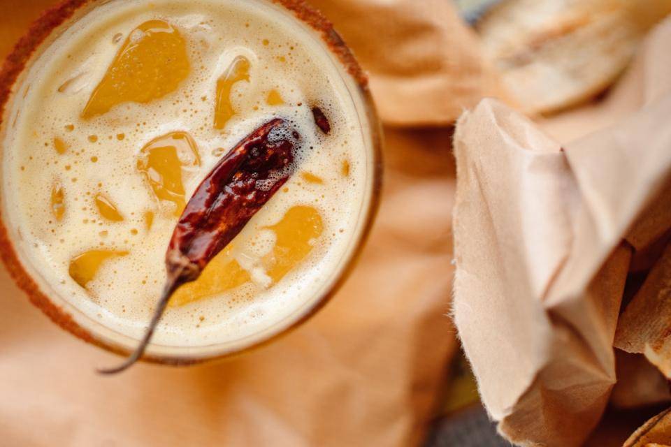 A sweet, frothy orange beverage with a dried chili