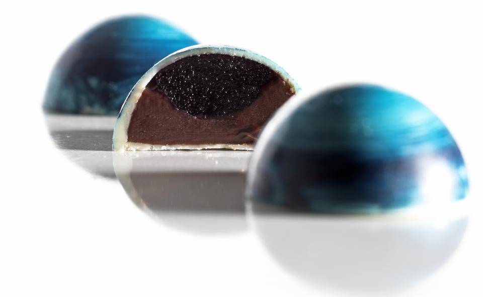 bombom azul cortado ao meio mostrando a camada de gelei de blueberry e chocolate