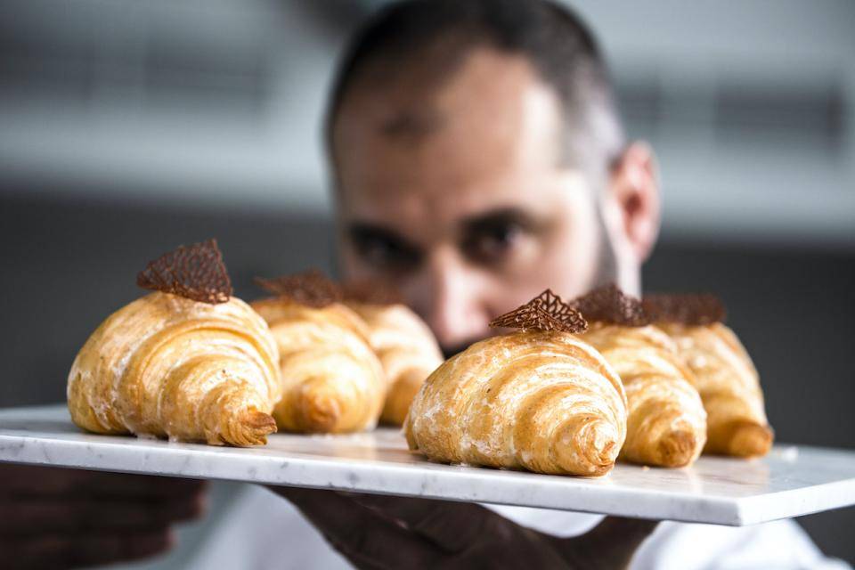 Chef Davide Comaschi examines a tray of plant-based chocolate croissants