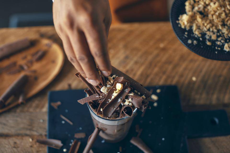 A decadent chocolate drink topped with real chocolate shavings and toasted nuts
