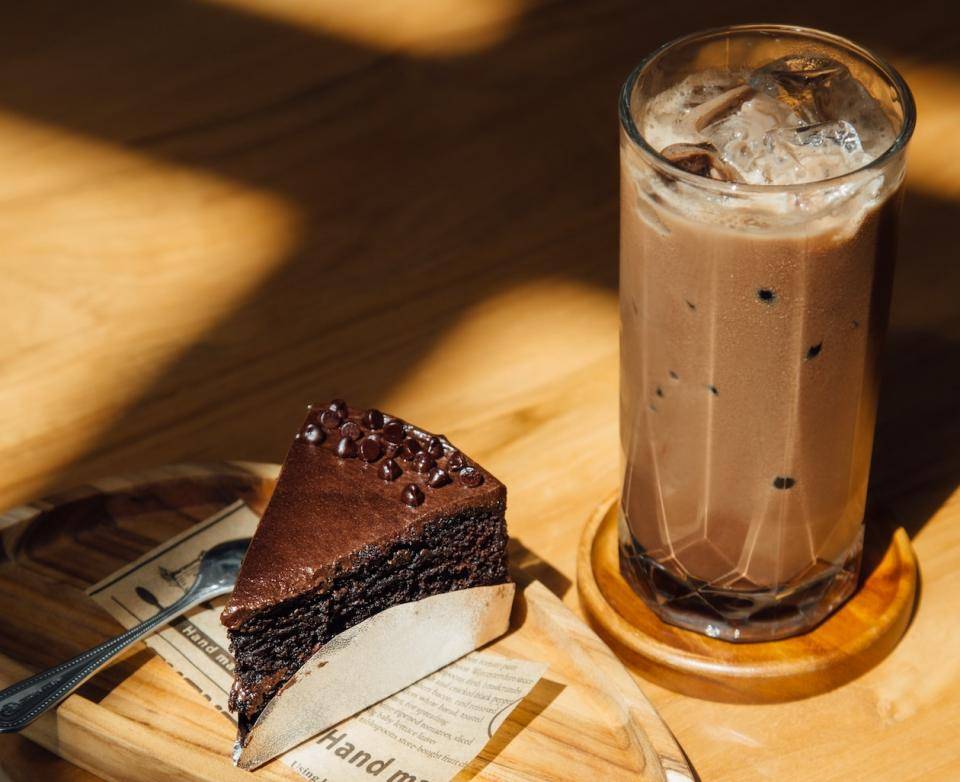 A small slice of chocolate cake paired with a cold, creamy chocolate beverage