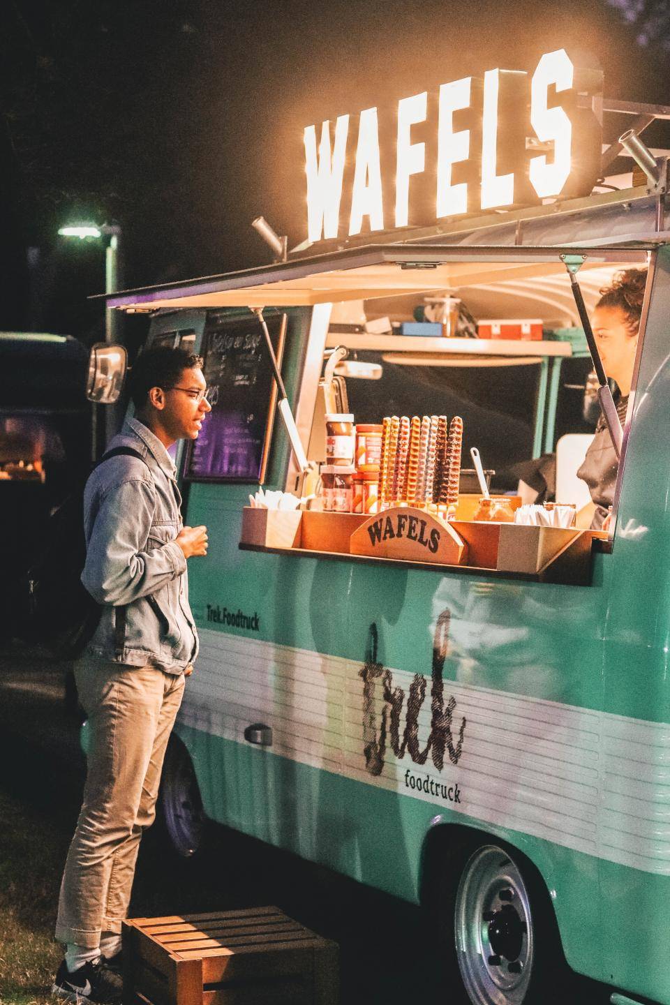 pesso em frente à um food truck de waflles com um neon 