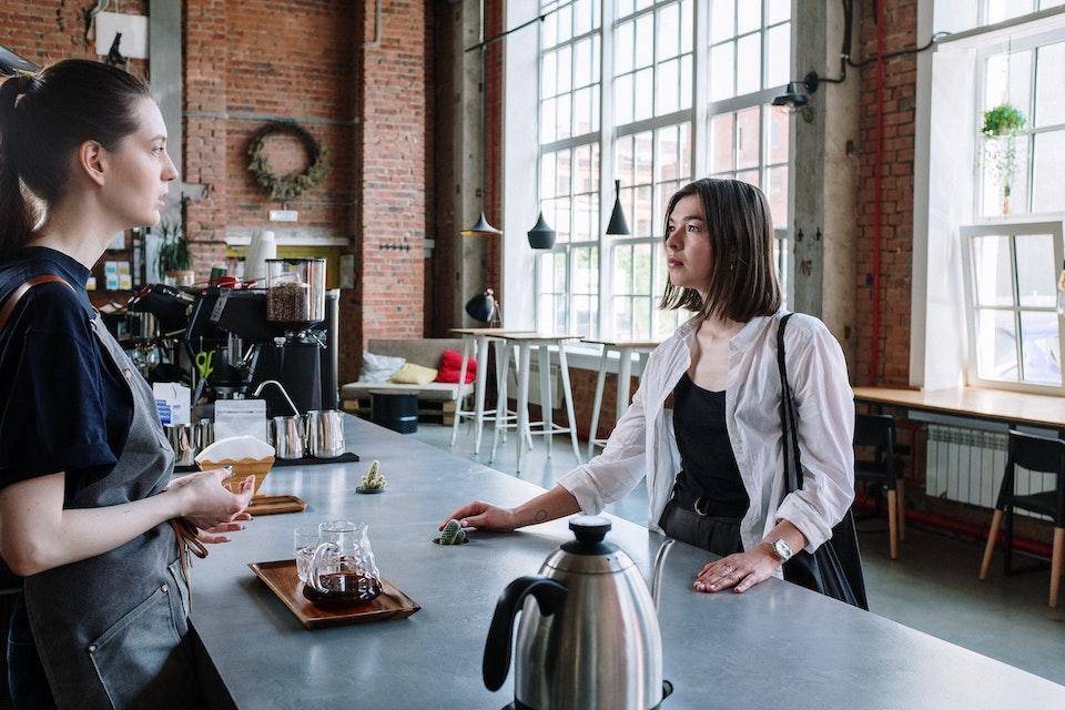 A cafe employee talks to a customer at the coffee counter