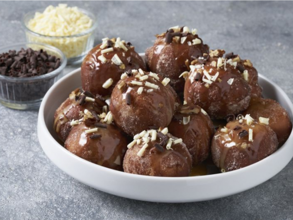 A plate piled with donut bits topped with pecans and chocolate