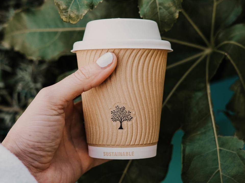 A coffee cup with a tree logo on the cup cozy