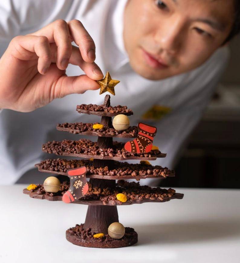 A chef puts a finishing touch on a chocolate christmas tree sculpture