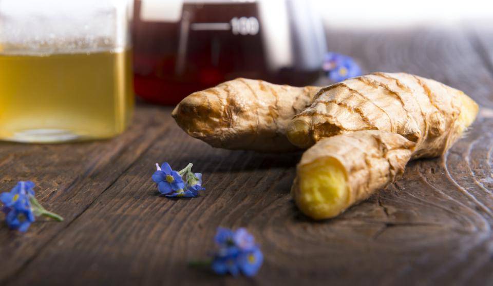A ginger root with bergamot flowers, ginger tea and infusion in the background