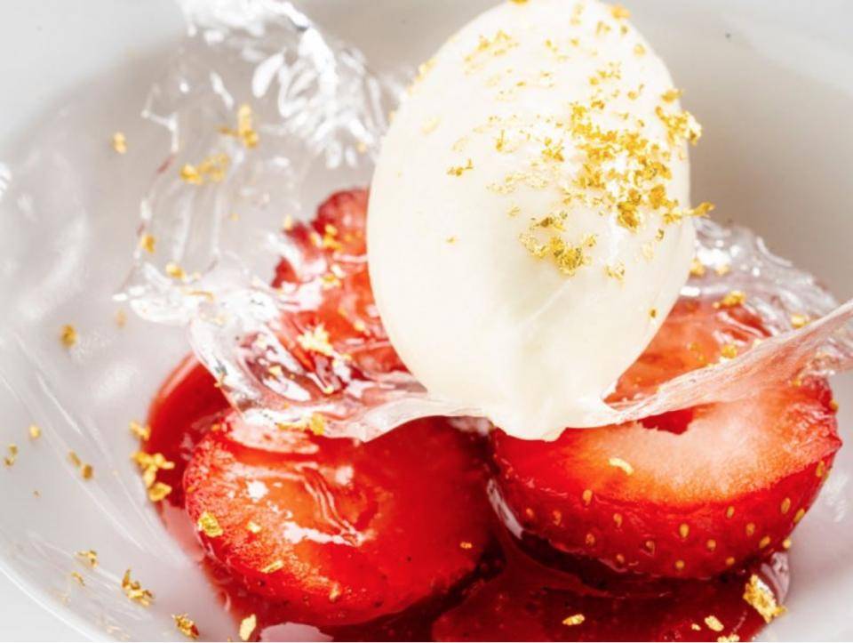 A dessert with strawberries, white chocolate ice cream, and sugar tuile
