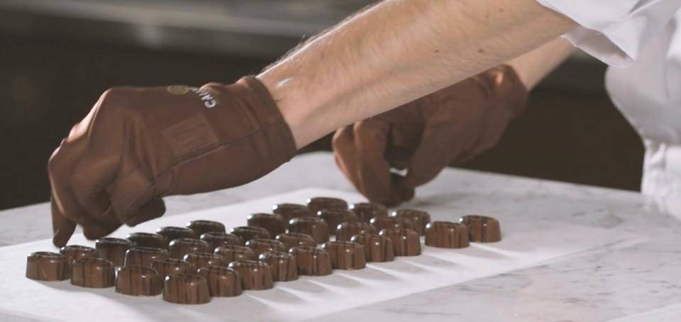 A chef uses gloves to handle finished bonbons