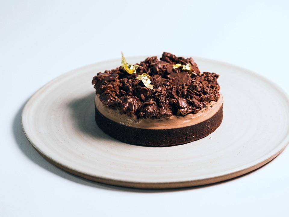 An elegant chocolate tart with gold leaf and a crunchy topping