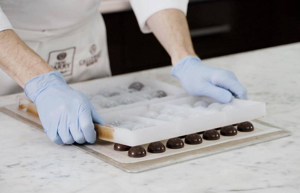 A chef wears latex gloves while unmolding bonbons