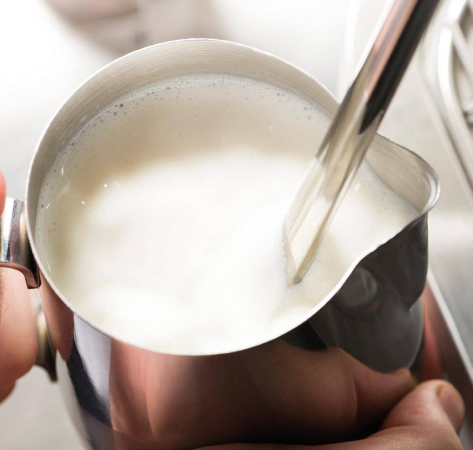 Schäumen Sie Milch auf (72 °C) und servieren Sie sie in einem hohen Glas.