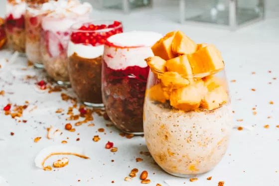 A row of glasses filled with colorful layers of fruit, yogurt, and granola 