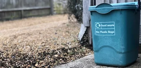 A bin labeled "food waste" in an alley