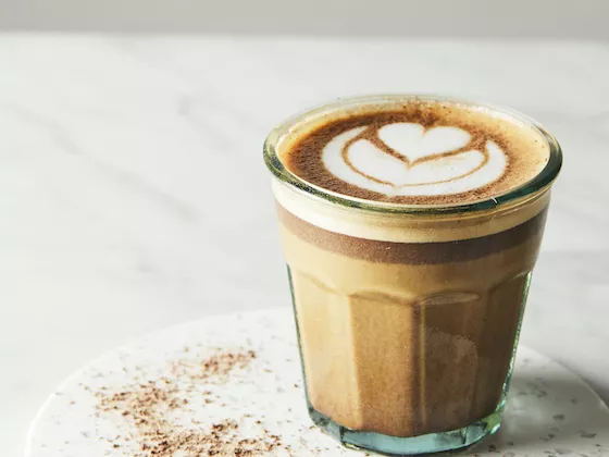 A chocolate coffee beverage with a latte art heart on top