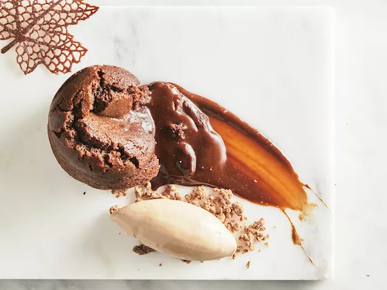 A plant-based chocolate lava cake with a liquid center on a marble background with ice cream
