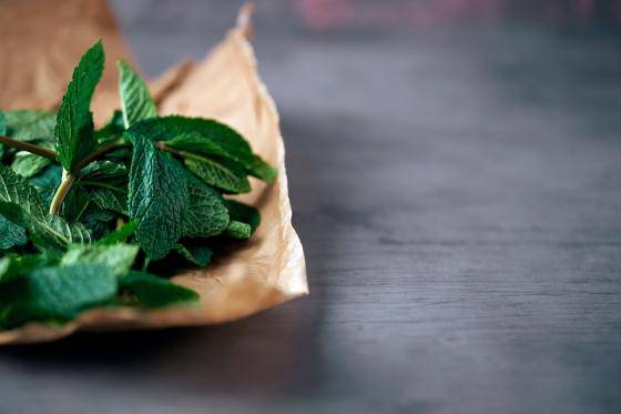 mint leaves on a piece of crinkled brown paper, on a grey countertop