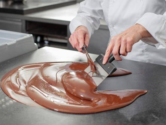 A chef tempering chocolate on a table top
