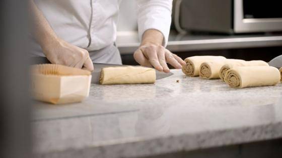 chef rolling dough on a bench