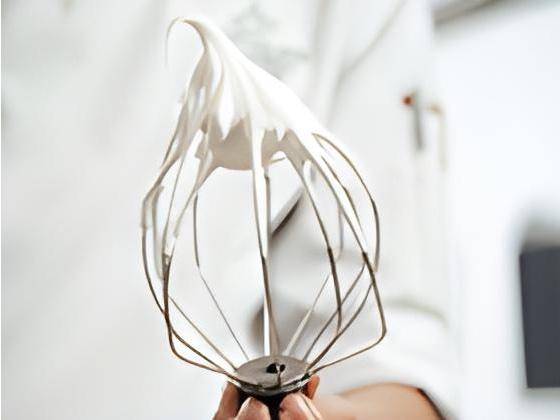 A meringue whipped to medium peaks on a whisk