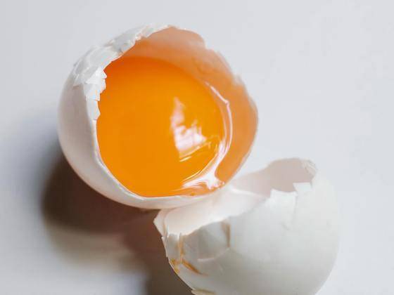A whole egg inside a cracked-open shell